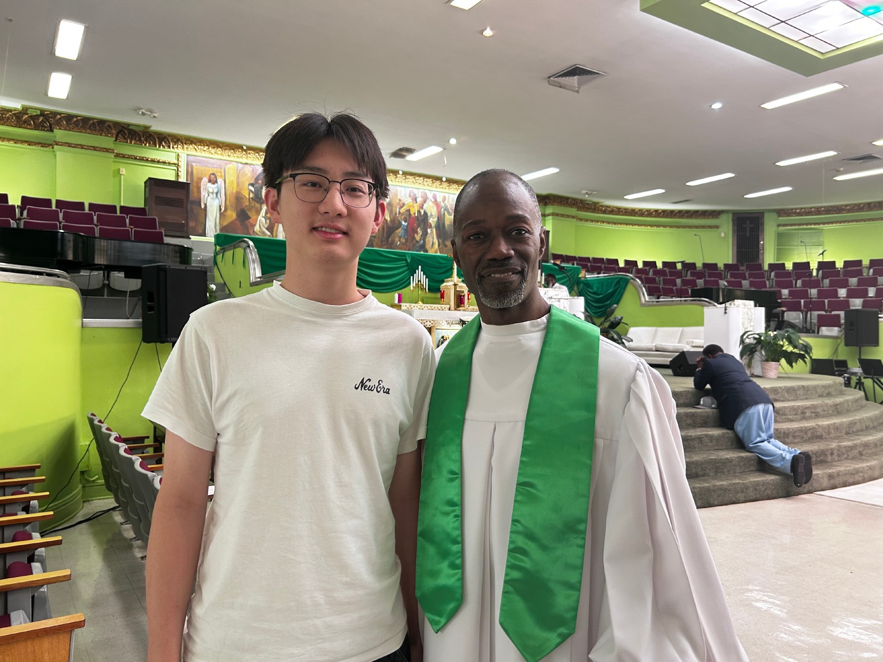 A student standing with a pastor in a green sanctuary